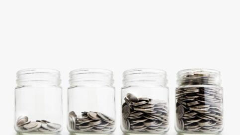 Four jars filled with varying amounts of coins