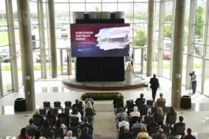 A presentation being held in the AgriLife Center. There are people in attendance, sitting in rows facing the screen. The screen is displaying a presentation entitled: "Automated Precision Phenotyping (App) Greenhouse". The speaker is using the podium.